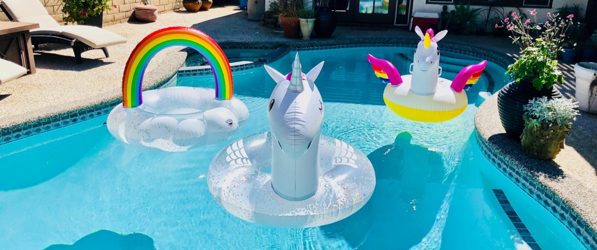 inflatable pool toys sit on the top of the water of a residential pool during a sunny day