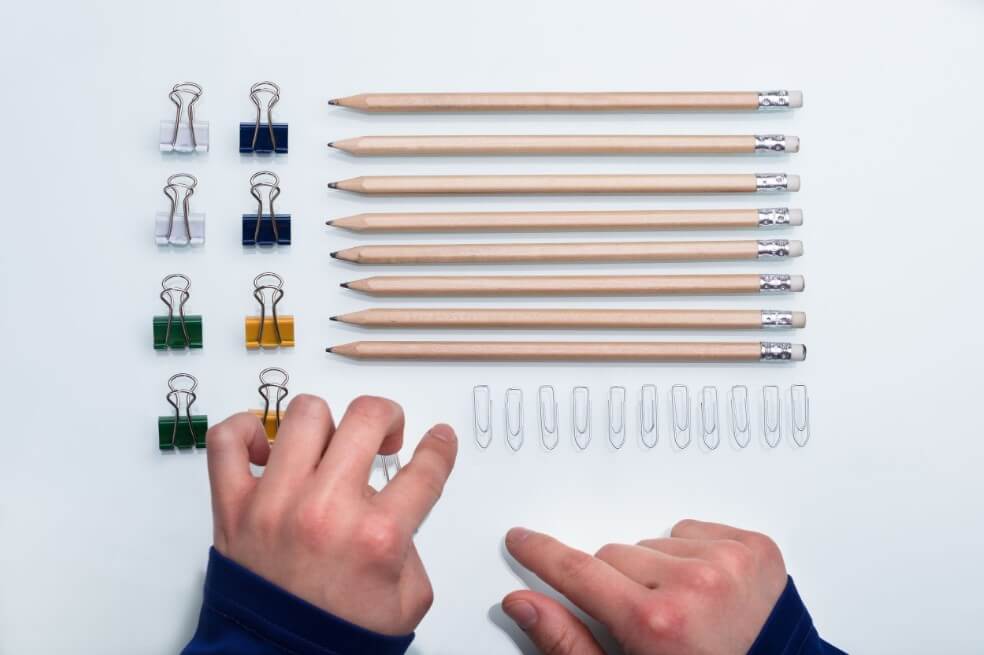 Hands organizing pencils and clips on a table