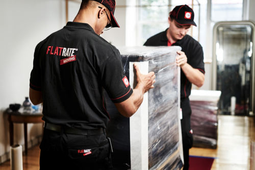 Movers carry a bubble wrapped piece of furniture