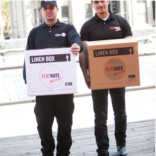 FlatRate movers carry some linen boxes on a street