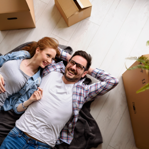 Happy customers lounge on the floor of their new place surrounded by boxes.