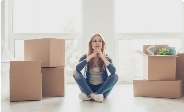 A woman sits on the floor with some packed boxes