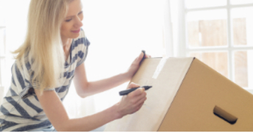 A person writes on a box with a marker