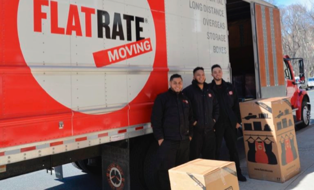 FlatRate movers pose in front of a FlatRate truck