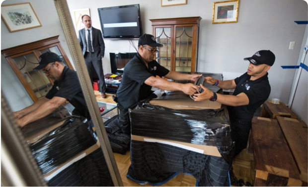 Elite movers work on wrapping furniture