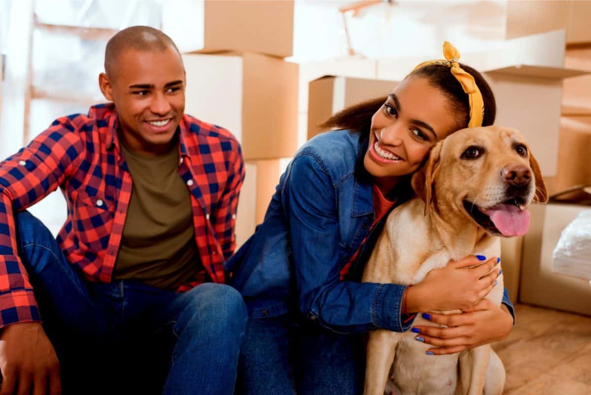Couple unpacking moving boxes with pet
