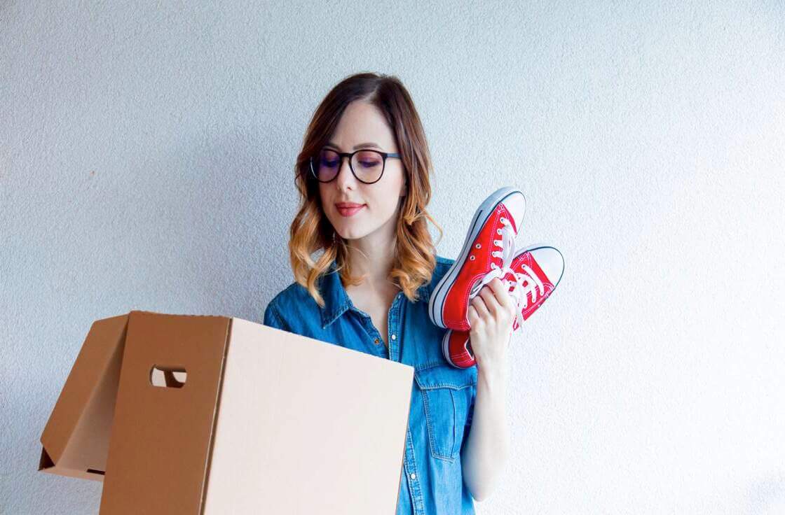 Lady packing red shoes into a box