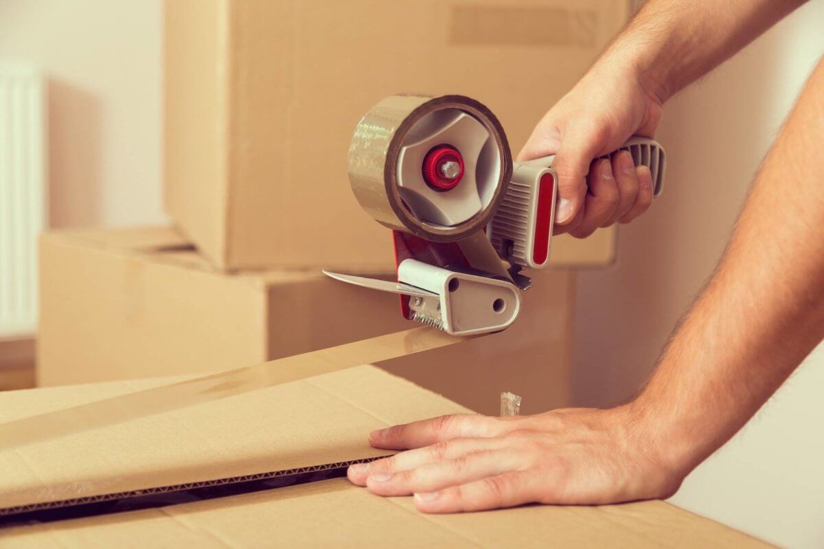 Man closing a box with tape