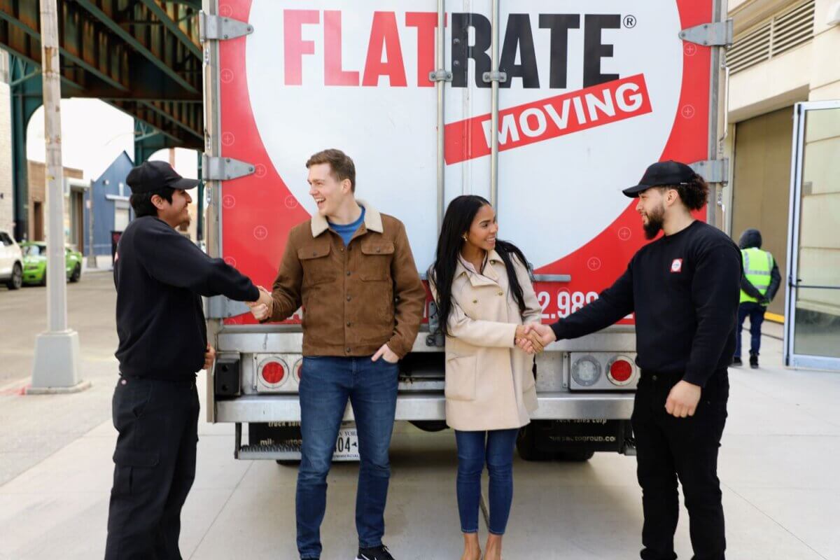 FlatRate movers and clients shaking hands in front of a FlatRate Moving truck.