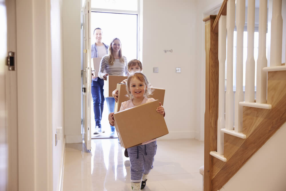 family carrying boxes into home