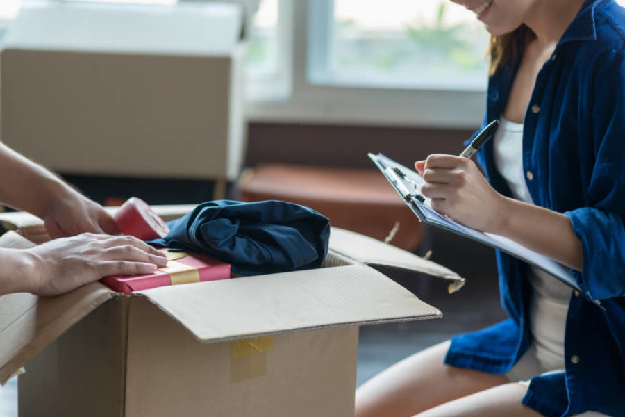 woman with checklist packing boxes closeup