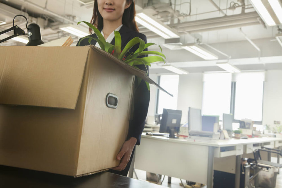 woman in an office carrying a moving box