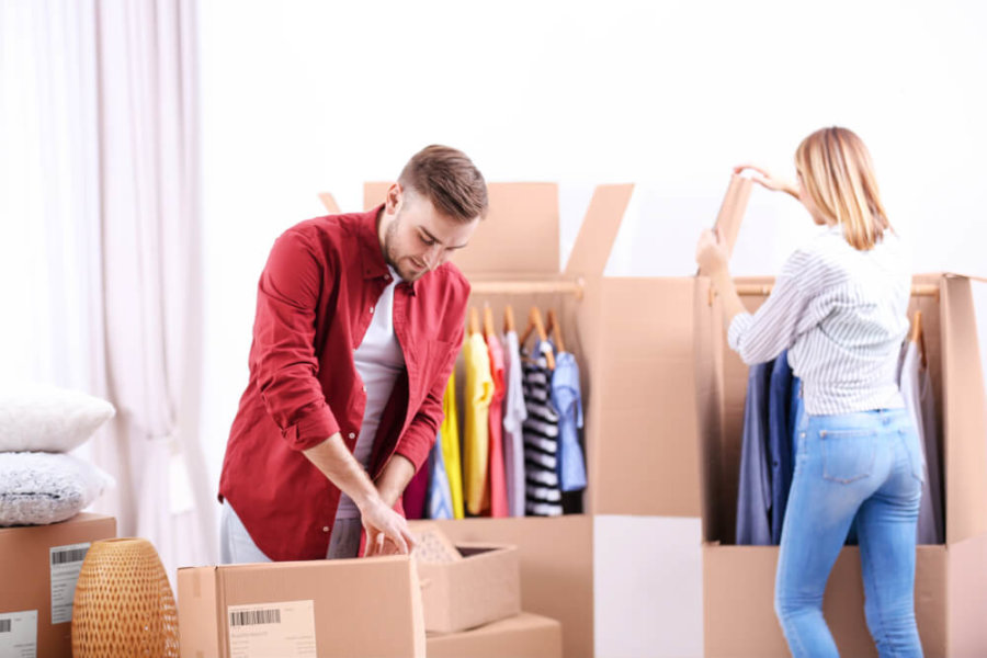 couple packing clothes in moving boxes