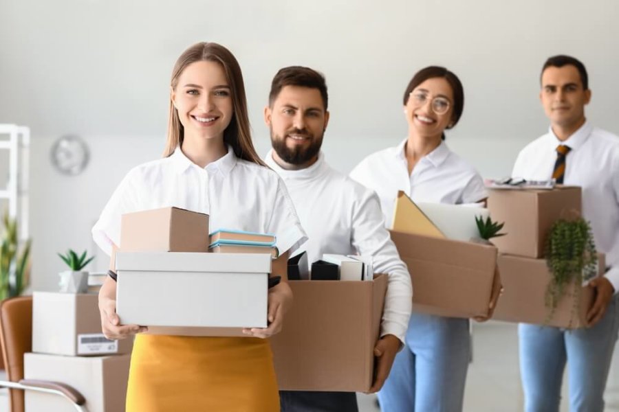 Four people moving office boxes