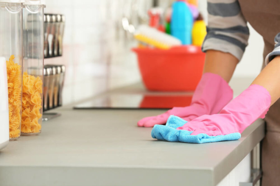 closeup of a person wearing gloves and cleaning the kitchen counter