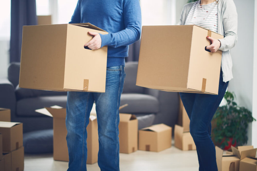 closeup of a man and woman carrying moving boxes