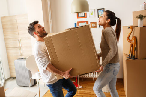 couple struggling to lift a heavy moving box