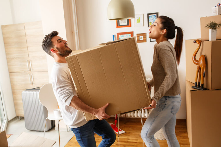 couple struggling to lift a heavy moving box