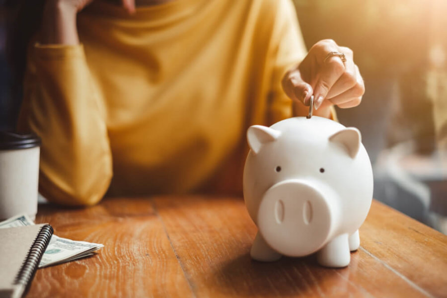 closeup of a woman putting coins in a piggy bank