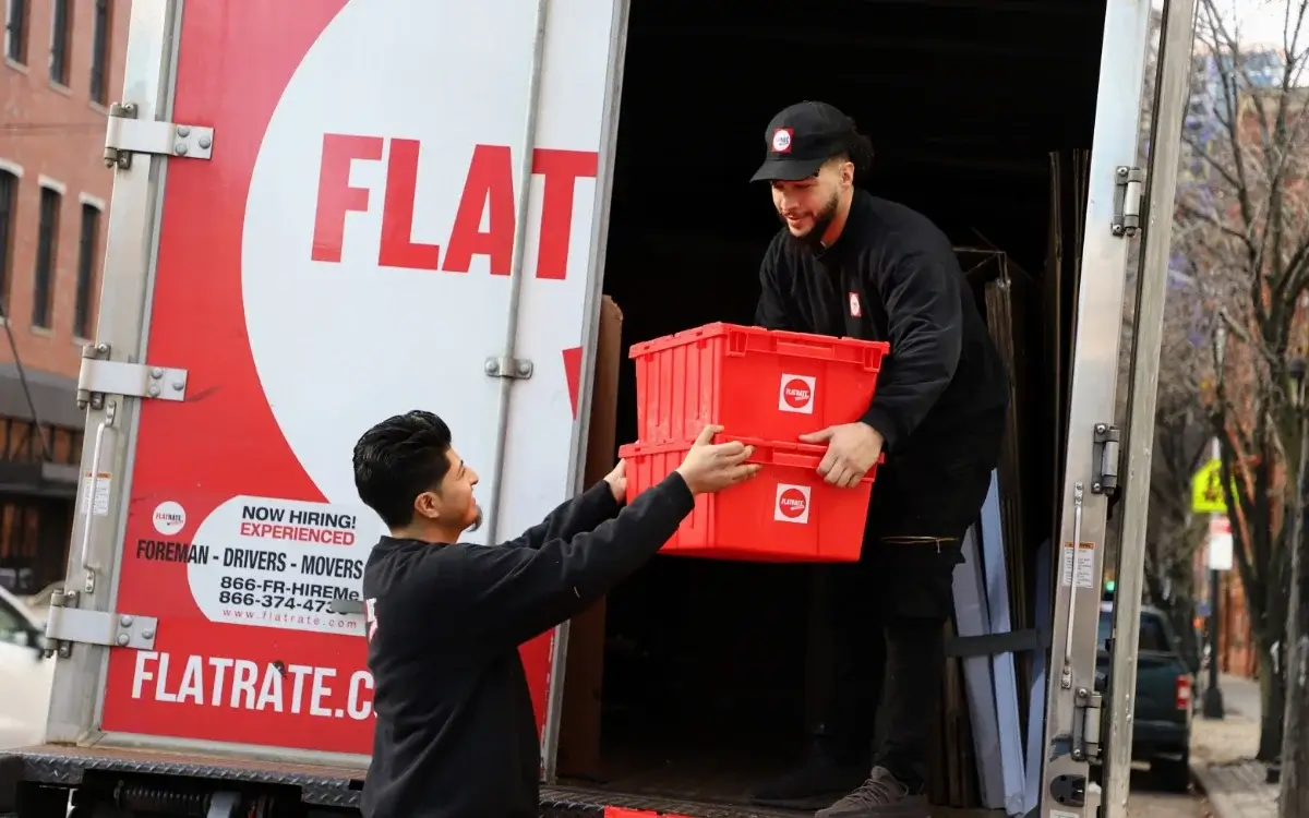 two guys loading red plastic boxes into the truck
