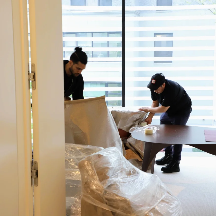 Two movers packing and wrapping furnitures
