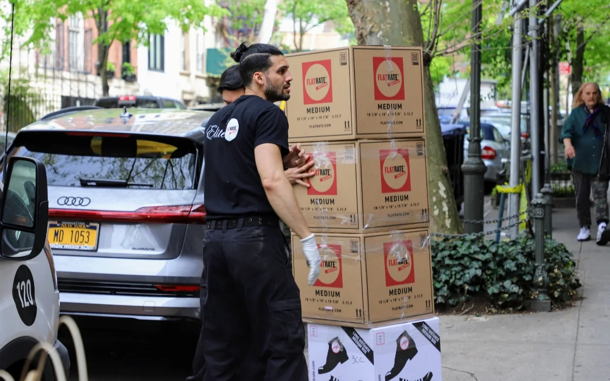Men moving a stack of boxes on the street