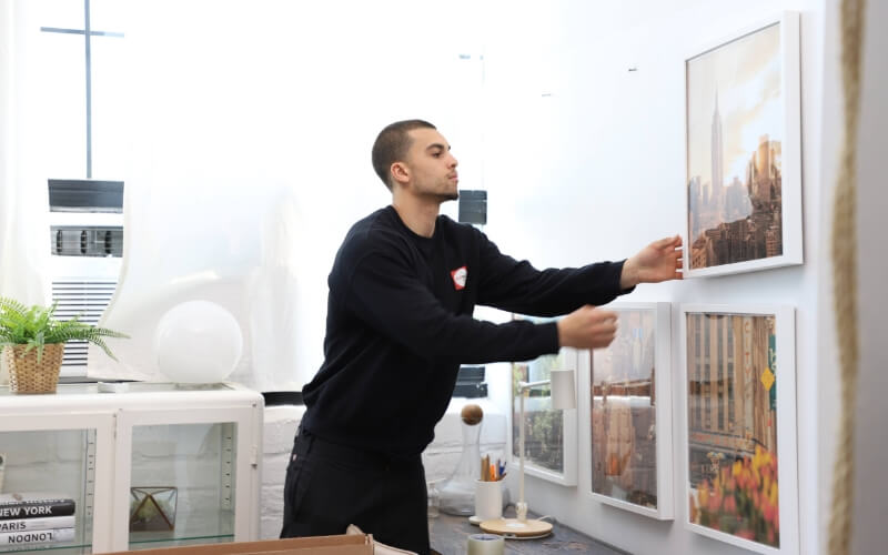 Flatrate mover organizing pictures on the wall