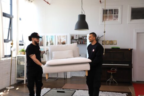 Two FlatRate Movers carrying a couch.