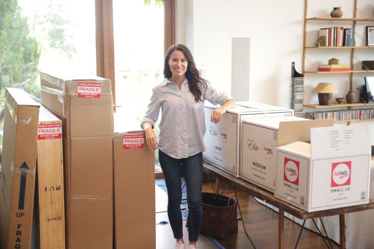 FlatRate moving client posing with packed moving boxes.