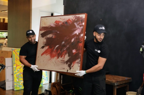 Two men carefully transporting an art picture