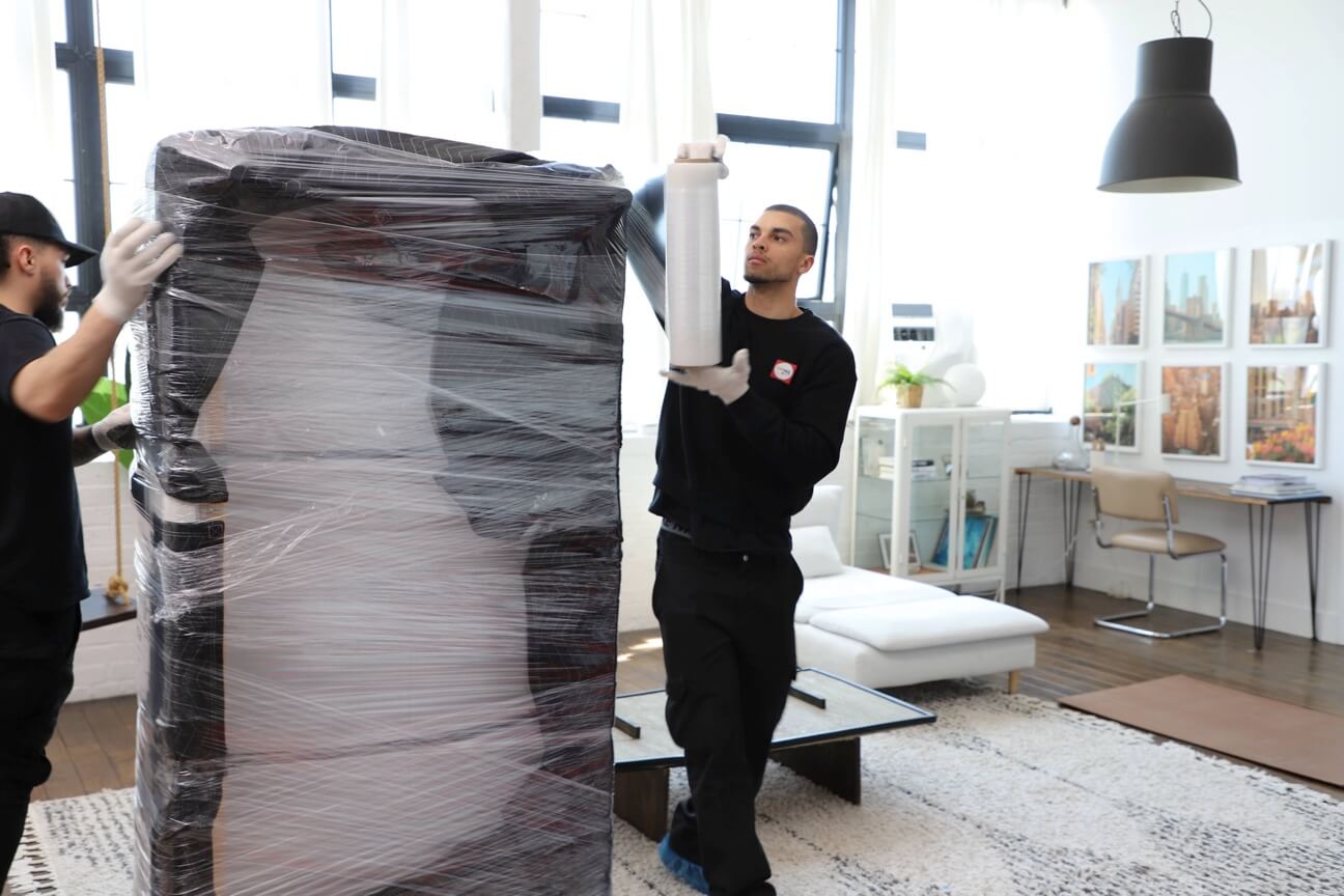 FlatRate movers wrapping a sofa